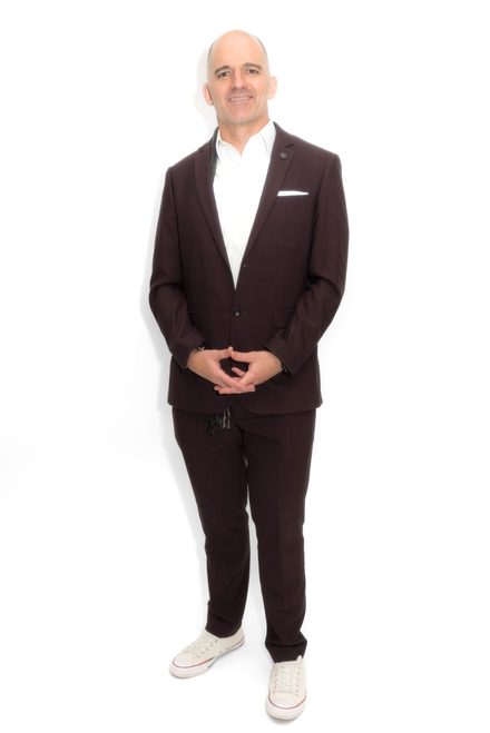 Jevon Perra standing in a dark suit and white sneakers